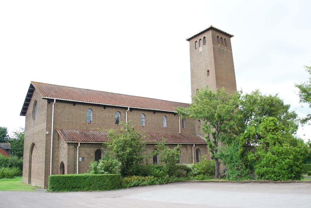 St Oswald's Church, a brick building with a tall square tower, seen from the car park